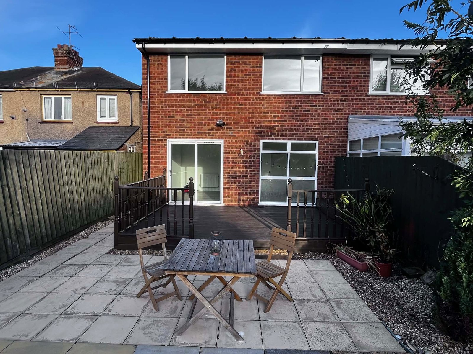 Freshly painted and tidied decking area, with garden furniture placed in front of the decking.